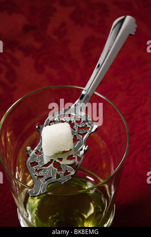 Absinth so eingerichtet, dass Wasser, Zuckerwürfel auf Absinth Löffel balanciert auf Cordon Glas gießen Stockfoto