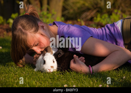 Junge Mädchen spielen mit zwei Kaninchen auf einer Wiese Stockfoto