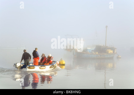 EIN KLEINES BOOT MIT FISCHERN, KÖPFE AUS IHREN GRÖßEREN BOOT IN DEN FRÜHEN MORGENNEBEL Stockfoto