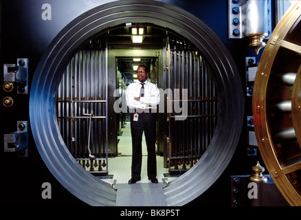 African American Bankangestellter in die sichere Tür zu einem großen Tresor stehe Stockfoto