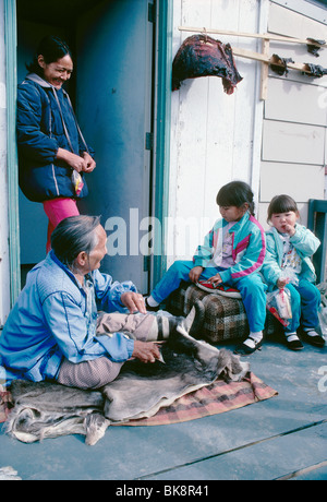 Drei Generationen von Inuit-Frau auf der Familie Veranda. Die Großmutter ist eine Karibu verstecken Schaben. Caribou Fleisch trocknet in der Sonne. Stockfoto