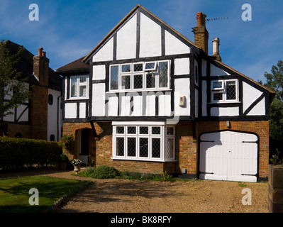 Mock Tudor schwarz-weiß 1930 Haus mit Garage und eine Fahrt in Esher, Surrey. VEREINIGTES KÖNIGREICH. Fotografiert an einem sonnigen Tag mit Sonne und blauer Himmel. Stockfoto