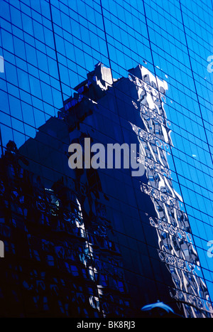 Abstrakte Ansicht eines Wolkenkratzers in den Fenstern eines modernen Bürogebäudes vor blauem Himmel in New York City, New York USA Stockfoto