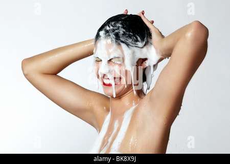 Fröhliche junge Frau in der Dusche mit Schaum im Haar Stockfoto