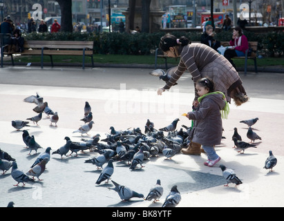 Mutter und Kind füttern Tauben auf Plaça de Catalunya Stockfoto