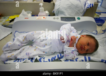 Ein kleines Mädchen wird im Krankenhaus, nur wenige Stunden nach der Geburt gewogen werden. Stockfoto
