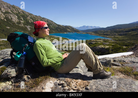 Junge Frau, Wanderer, Backpacker, sitzt auf einem Felsen, ausruhen, genießen Panorama, Deep Lake, historische Chilkoot Pass, Chilkoot Trai Stockfoto