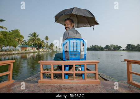 Hausboot-Kapitän Lenkung sein traditionelles Kettuvallam Boot in Backwaters von Kerala, Indien. Stockfoto