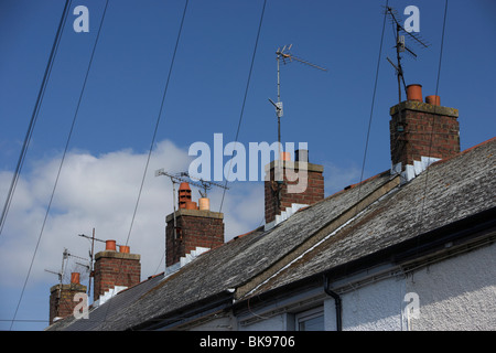 Zeile rot gemauerten Schornstein auf Reihenhaus Dächer mit Fernsehantennen und obenliegende Telefon Kabel im Vereinigten Königreich Stockfoto