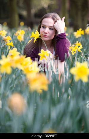 Ein junges Mädchen schaut nachdenklich in einem Feld von Narzissen. Stockfoto