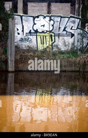 Graffiti an der Wand reflektiert am Fluss Water of Leith in Edinburgh, Schottland. Stockfoto