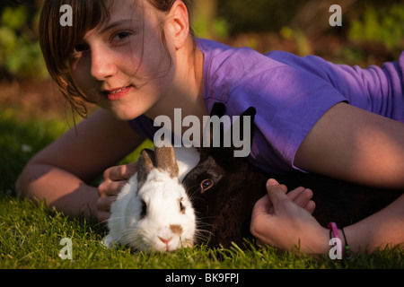 Junge Mädchen spielen mit zwei Kaninchen auf einer Wiese Stockfoto