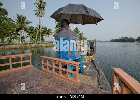 Hausboot-Kapitän Lenkung sein traditionelles Kettuvallam Boot in Backwaters von Kerala, Indien. Stockfoto