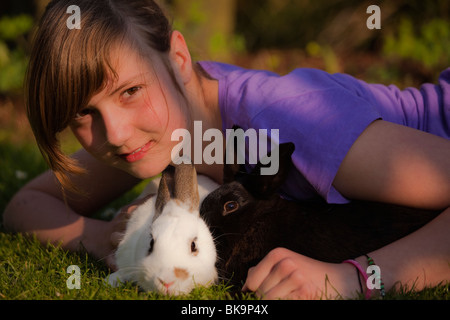 Junge Mädchen spielen mit zwei Kaninchen auf einer Wiese Stockfoto