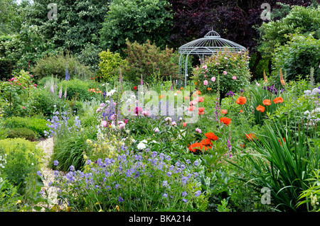 Cranesbills (Geranien), orientalischer Mohn (Papaver Orientale), Rosen (Rosa), Pfingstrosen (Paeonia) und Fingerhut (Digitalis) mit Garten Pavillon. Design: Stockfoto