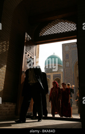 Usbekische Einreisende in die Kalyan Moschee in Buchara, Usbekistan. Mir i Arab Medrese ist im Hintergrund. Stockfoto