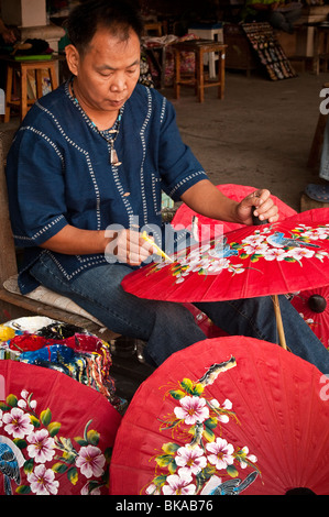 Mann Malerei Sonnenschirme an der Schirmfabrik in Chiang Mai, Thailand. Stockfoto