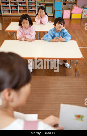 Kindergartenkinder, Lehrer reden hören Stockfoto