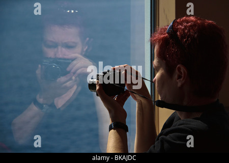 Frau mit Kamera spiegelt sich im Fenster der Fähre, Seattle, Washington Stockfoto