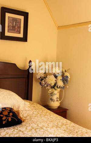 Ecke aus einem Schlafzimmer mit Bild und Krug mit Blumen Stockfoto