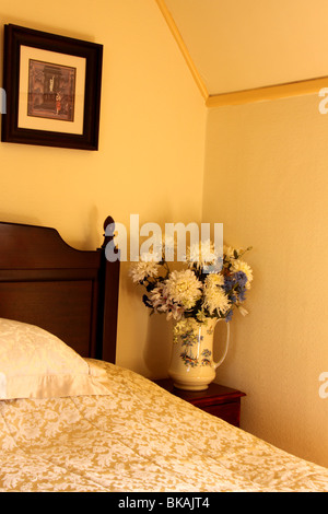 Ecke aus einem Schlafzimmer mit Bild und Krug mit Blumen Stockfoto