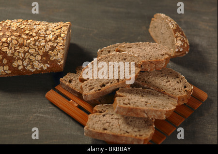 Getreide-Laib Brotscheiben in dunklem Holz Stockfoto