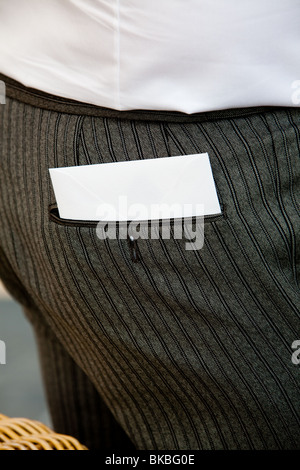 Das Bild zeigt ein Stück Papier ragte aus der Gesäßtasche eines Mannes in einem Kostüm. Stockfoto