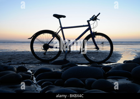 Mountainbike am Strand bei Sonnenuntergang, Westward Ho, North Devon, UK Stockfoto