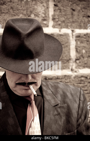 Ein Mann gekleidet wie ein Spiv gegen eine Wand, während einer Veranstaltung der 1940er Jahre in Haworth, Vereinigtes Königreich steht Stockfoto