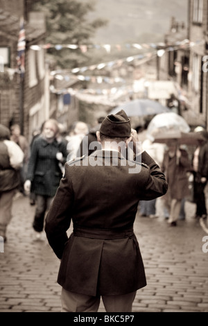 Ein Mann im Kostüm hält seinen Hut, während er auf einer gepflasterten Straße während einer Veranstaltung der 1940er Jahre in Haworth, Vereinigtes Königreich geht Stockfoto