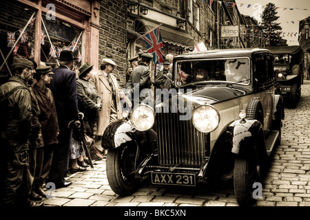 Eine alte altmodische Auto fährt hinunter eine Straße mit der 1940er Jahre Zeichen während einer Veranstaltung in Haworth, Vereinigtes Königreich Stockfoto