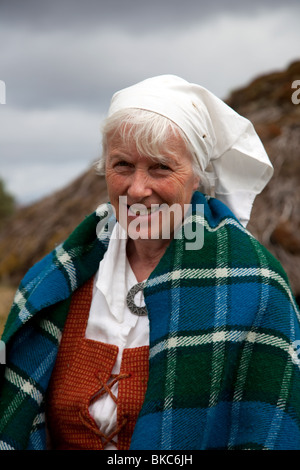 Frau in traditioneller Kleidung, und strohgedeckten Schottischen croft bei Highland Folk Museum, Sehenswürdigkeit in Aviemore, Highlands, Schottland, Großbritannien Stockfoto