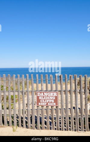 Strand-Zaun und Warnung am Rand der Klippe zum Meer auf Cape Cod National Seashore, Nauset Licht Strand, Eastham, Cape Cod USA unterzeichnen Stockfoto