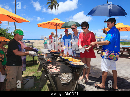 Barbecue am Strand von Nevis, für die Passagiere auf dem Kreuzfahrtschiff vor Anker in der Ferne. Stockfoto