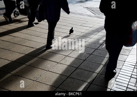 Silhouetten von Menschen zu Fuß entlang einer Stadt-Pflaster Stockfoto
