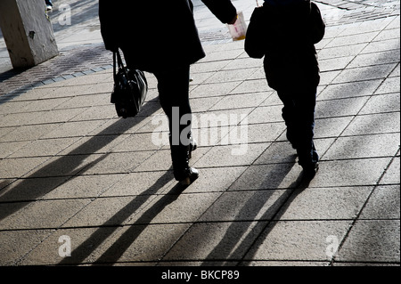 Silhouetten von Menschen zu Fuß entlang einer Stadt-Pflaster Stockfoto