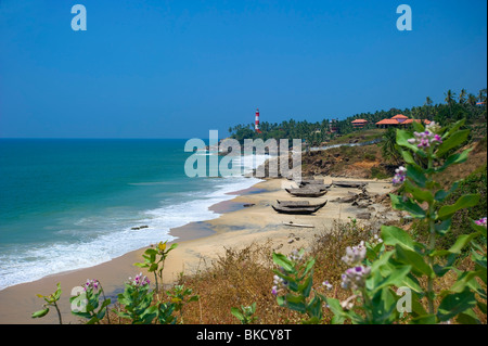 Angelboote/Fischerboote am Rockholm Strand mit Leuchtturm auf Landzunge, Kovalam, Kerala, Indien Stockfoto