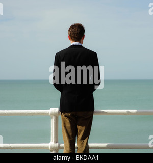 Rückansicht eines einzigen Mannes, abgewandten, stehen allein Blick auf das Meer an einem Sommertag Stockfoto