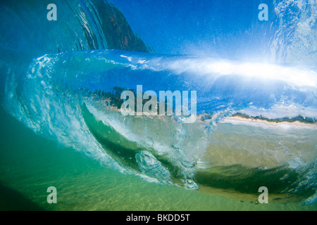 Die flüssigen Glasmalerei, gebildet durch eine brechende Welle im kristallklaren Wasser umhüllt das Bild des romantisch zu zweit am Strand. Stockfoto