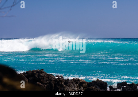 Die Passatwinde wehen ihre Plumeria riechenden Atem nach einem türkisfarbenen Meer Maui und eine Surfer spielt in den Böen. Stockfoto