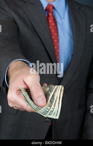 Ein Geschäftsmann, ein Bündel Geldscheine zu erweitern, als ob eine Auszahlung anbieten oder das bezahlen von waren. Stockfoto