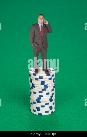 Ein Mann steht auf einen Stapel von Pokerchips Berufung in seine Wette. Stockfoto