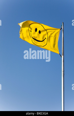 Gelber Smiley Gesicht Flagge vor einem strahlend blauen Himmel. Stockfoto