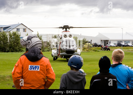 Menschen versammeln sich um einen Hubschrauber von der isländischen Küstenwache, Vogar in Vatnsleysustrond, Island. Stockfoto