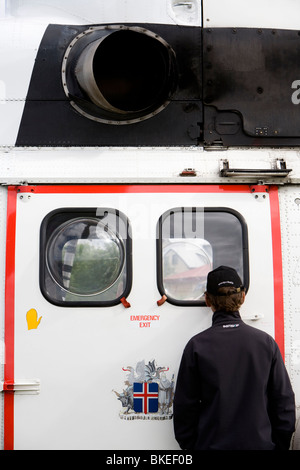 Menschen versammeln sich um einen Hubschrauber von der isländischen Küstenwache, Vogar in Vatnsleysustrond, Island. Stockfoto