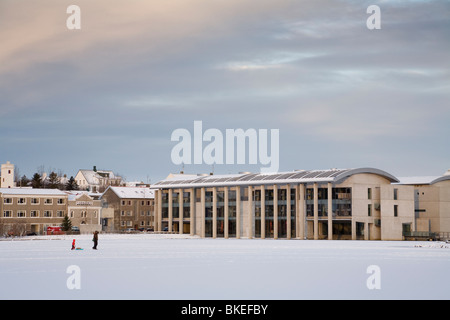 Menschen zu Fuß vorbei an Rathaus von Reykjavik auf zugefrorenen See Tjörnin. Die Innenstadt von Reykjavik Island Stockfoto