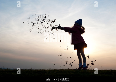 Junges Mädchen Spaß Blätter zu werfen. Silhouette Stockfoto