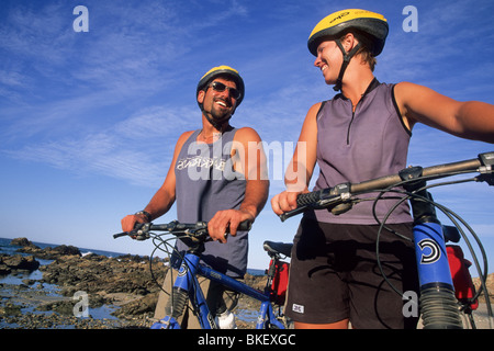 Paare, die Fahrräder am Strand. Stockfoto