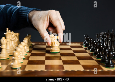 Hand bewegt eine Schachfigur Ritter auf hölzernen Schachbrett Stockfoto