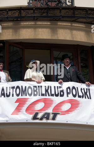 Männer und Frauen auf Balkon mit Feier Banner feiert 100 Jahre polnische Automobile Club, Hotel Bristol, Warsaw, Polen Stockfoto